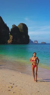 Kırmızı bikinili kendine güvenen kadın Phra Nang Sahili, Krabi, Tayland 'da poz veriyor. Railay yakınlarında Ao Nang turlarında sık sık ziyaret edilen manzaralı bir yer. Moda, seyahat veya tropikal yaşam tarzı temaları için ideal.