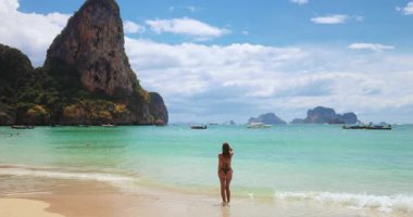 Bir kadın, Tayland, Krabi 'deki Railay Plajı' nda denizin tadını çıkarıyor. Uçurumlar ve kristal sularla çevrili olan bölge, Güneydoğu Asya 'nın en iyi seyahat noktalarından biri. Turizm ve tropikal yaşam tarzı için harika.