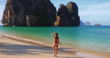 Formda kadın, Tayland, Krabi Phra Nang Sahili 'nde kumsal anlarından hoşlanıyor. Railay yakınlarında ve Ao Nang 'dan gelen turlarla popüler. Seyahat reklamları, mayo başlıkları ve tropikal yaşam tarzı çekimleri için harika..