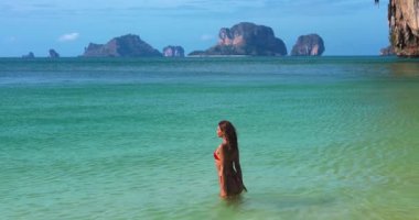 Bronzlaşmış kadın, Krabi Phra Nang Sahili 'nde, tropikal denizde neşeyle su sıçratıyor. Railay yakınlarında, Ao Nang tekne turlarının önemli bir parçası. Yaşam tarzı, özgürlük ve plaj tatili temaları için mükemmel..