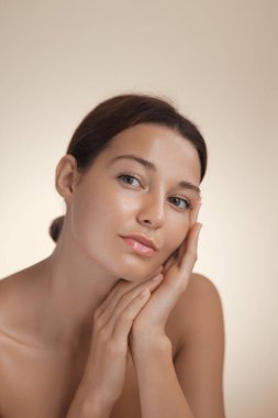 Kusursuz, pırıl pırıl cildi yüzüne dokunan, doğal güzelliği ve cildini sembolize eden beyaz bir kadının portresi. Sağlık, kaplıca ve kişisel bakım kavramları için ideal..