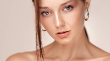 Işık saçan, parlak dudakları olan, halka küpeler takan şık bir kadının stüdyo görüntüleri. Cilt reklamları, kozmetik kampanyaları ya da güzellik içeriği için mükemmel..