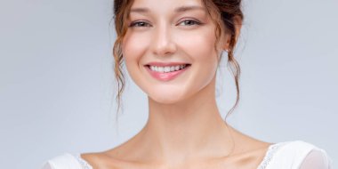 Yüzü parlayan ve makyajı az olan gülümseyen beyaz bir kadının stüdyo portresi. Güzellik, cilt bakımı, sağlık promosyonları ve kozmetik endüstrisi için ideal..