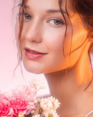 Parlayan derisi ve çiçekleriyle kameraya bakan güzel beyaz bir kadın. Kozmetik, parfüm, cilt bakımı, çiçek güzelliği ve lüks markalaşma için yüksek kaliteli görüntü.