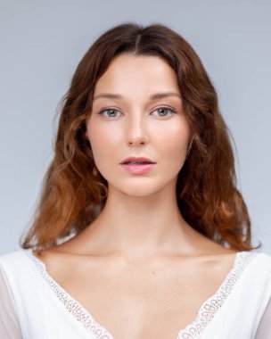 Parlak tenli, beyaz dantelli, doğal güzellik, cilt bakımı, sağlıklılık ve temiz yaşam tarzı içeriği için ideal genç beyaz bir kadının minimalist stüdyo portresi..