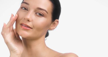 Yanağına dokunan, parlak cilt ve parlak dudaklar gösteren beyaz bir kadının yüksek kaliteli portresi. Cilt reklamları, güzellik ürünleri ve kozmetik promosyon tasarımları için mükemmel..