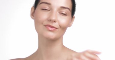 Beyaz kadın kameraya güvenle bakarken yüzüne ve çenesine hafifçe dokunuyor. Yaşlanma karşıtı cilt bakımı reklamları, temiz güzellik tanıtımları ve sağlıklı marka görselleri için ideal..