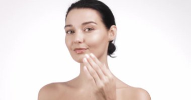 Modayı takip eden güzellik modeli cilt kremini parlak cilt ve ince dokunuşlarla uyguluyor. Premium kozmetik reklamları, yüz bakımı dersleri, yumuşak odaklı sağlık reklamları ve ürün markalaşması için ideal..