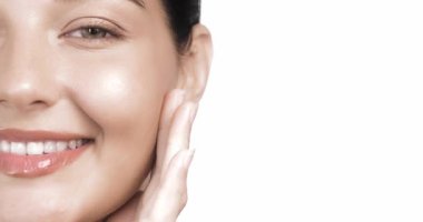 Parmaklarını yüzünde gezdirirken hafifçe gülümseyen genç bir kadının aşırı yakın çekimi. Cilt bakımı, yüz parıltısı, kozmetik, güzellik ve refah temalı ticari içerik için mükemmel.