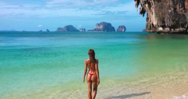 Genç bikini modeli, Krabi 'deki Phra Nang Sahili' nde çıplak ayakla duruyor. Ko Poda 'da ise kireçtaşı kayalıkları var. Yüksek kaliteli yaşam tarzı ve egzotik, sakin atmosferli seyahat stoku konsepti.
