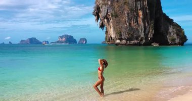 Seksi bikini modeli, uzaktaki Ko Rang ve Ko Poda adalarıyla Phra Nang Plajı 'ndaki berrak tropikal sularda güven içinde poz veriyor. Seyahat, güzellik, tanıtım ve egzotik yaşam tarzı reklamları için ideal..