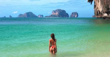 Krabi Phra Nang Sahili 'nde turkuaz denizde oynayan seksi bikini modelinin arka görüntüsü. Arka planda Ko Poda Adası var. Tropik tatil, güzellik ve seyahat yaşam tarzı promosyonları için ideal..