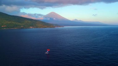 Agung Yanardağı ve küçük bir tekne ile yüksek kaliteli gündoğumu havası. Seyahat tanıtımları, turizm kampanyaları ve sakin okyanus manzaraları için ideal..