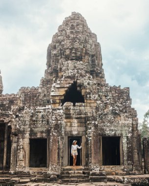 Kamboçya 'nın Angkor Wat kentindeki Bayon Tapınağı' nın girişini araştıran günlük kıyafetli bir kadın turist. Yayın, seyahat reklamları ve kültür turizmi için yüksek kalite kavramsal fotoğraf ideal.