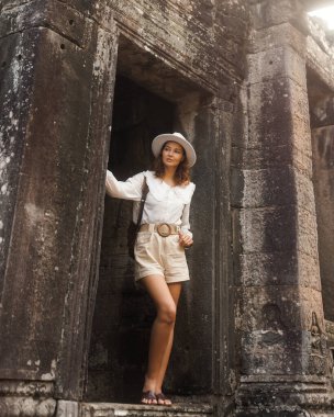 Kamboçya 'daki Antik Tapınak Harabelerini Keşfeden Solo Kadın Gezgin, seyahat blogları, turizm kampanyaları ve dünya çapında kültür mirası, macera ve dikkatli yavaş turizmi gösteren seyahat tutkusu reklamları için ideal..