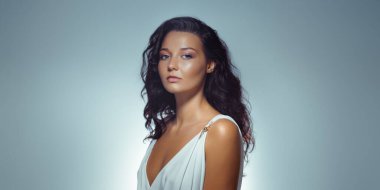 Beyaz, klasik Yunan tarzı bir elbise giymiş, çarpıcı, beyaz bir kadının yüksek kalite yakın çekimi. Güzellik, cilt bakımı, moda kampanyaları ve lüks promosyon malzemeleri için ideal..