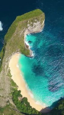 Bali, Nusa Penida 'daki Kelingking Sahili' nin dramatik uçurumları, altın kumları ve turkuaz dalgaları olan insansız hava aracı görüntüleri. Seyahat reklamları, tatiller, turizm tanıtımları, tropikal kaçış temaları için ideal.