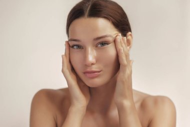 Kafkasyalı kadın nazikçe şakaklarının yanındaki deriyi yüzme efekti taklidi yaparak iki eliyle çekiyor. Cilt bakımı, estetik ameliyatlar veya yaşlanmayı önleyen güzellik reklamları için ideal..