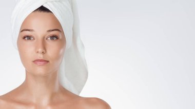 Beyaz arka planda havluya sarılı saçları olan, cilt bakımı, spa ve sağlık markaları, güzellik blogları, kozmetik ürün afişleri ve temiz yaşam tarzı reklamları için ideal genç bir kadın..