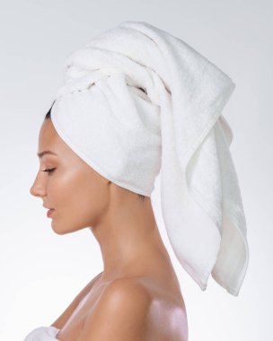 Profil güzellik portresi konsepti: beyaz arka planda havlu türbanlı beyaz kadın, temiz stüdyo. Yüksek kalite cilt bakımı, kaplıca ve sağlık afişi, kozmetik ürünleri için kopya alanı olan en düşük şablon.