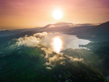 Bratan volkanik arazisi tarafından çerçevelenen Bali 'nin Buyan Gölü üzerinde altın gün doğumu, seyahat pazarlama, eko-turizm içeriği ve prim doğa editörleri için mükemmel bir kavramsal yüksek kaliteli promosyon fotoğrafı. 