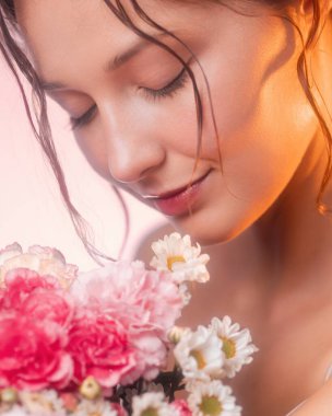 Beyaz tenli, çiçek kokan genç bir kadının yakın çekimi. Parfüm, kozmetik, cilt bakımı, sağlık veya çiçek yaşam tarzı reklamları için yüksek kalite görüntü ideali.