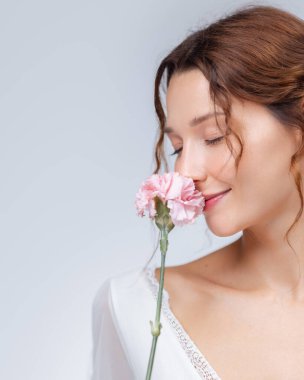 Pembe karanfil çiçeğinin kokusundan hoşlanan Kafkas bir kadının serin stüdyo portresi. Onun kapalı gözleri ve nazik gülümsemesi huzuru, sağlığı, kadınlığı ve doğal güzelliği çağrıştırıyor..