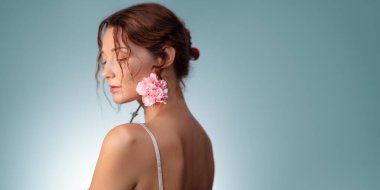 Parlak derili ve pembe çiçekli zarif bir kadının, pastel mavi bir arka planda çekilmiş şık bir stüdyo görüntüsü. Güzellik reklamları, cilt bakımı, moda ve kozmetik markalar için mükemmel..