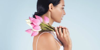 Elinde pembe nilüfer çiçekleri tutan Asyalı bir kadının profili güzellik ve huzuru simgeliyor. Sağlık, kaplıca ve cilt bakımı için mükemmel. Doğal zarafet ve sükuneti ön plana çıkarıyor..