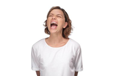 Beyaz tişörtlü, gözleri kapalı ve ağzı açık bağıran genç bir kadın. Stres, hüsran, duygusal rahatlama, tükenme, zihinsel sağlık veya yüksek enerji kavramları için idealdir..