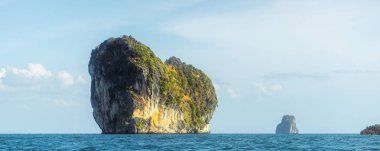 Dramatik kireçtaşı karst adası Tayland 'ın Krabi kentindeki Andaman Denizi' nden yükselmekte, uçurumlar, yeşil yapraklar ve dalgalı mavi sularla. Konsept: Turizm, seyahat afişi, asgari deniz manzarası, yüksek kalite.