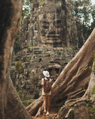 Angkor Thom 'daki Bayon suratı, Prasat Bayon Tapınağı' nın Antik Kapısı, Angkor Thom ve kadın turist Siem hasadı, Kamboçya 'da popüler bir turistik ilgi odağı.