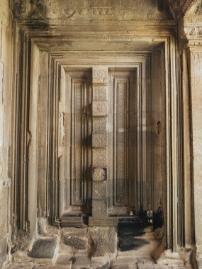 Angkor Wat 'ın içi katmanlı Khmer kalıpları ve süslü kumtaşı oymalarıyla dolu, yumuşak tapınak ışığına yakalanmış. Seyahat rehberleri ve miras medyası için yüksek kaliteli resim.