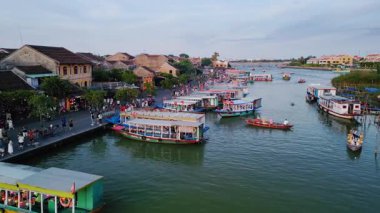 Thu Bon Nehri 'ndeki nehir kenarı tekne gezisi sahnesi. Rıhtım güvertesi ve renkli turistik tekneleri var. Seyahat reklamları, turizm videoları, Vietnam kültürü ve yaz tatili temaları için ideal.