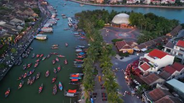 Hoi üzerindeki hava alacakaranlığı küçük tekneler, palmiye adası ve parıldayan eski şehir sokaklarıyla dolu bir nehir. Seyahat reklamları, turizm tanıtımları, Vietnam kültürü, festivaller ve sinema belgeselleri için ideal.