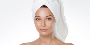 Doğal cilt bakımı ve reklam konsepti: temiz beyaz stüdyo arka planında havluya sarılı saçı olan beyaz bir kadının yakın çekimi. Yüksek kaliteli güzellik portresi spa ve ekommerce için idealdir..