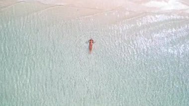 Beyaz kum plajı yakınında, kristal berrak tropikal denizde yüzen bir kadının havadan görünüşü, minimalist yaz tatili konsepti. Lüks seyahat, sağlık, tatil köyü ve yaşam tarzı için yüksek kaliteli imaj