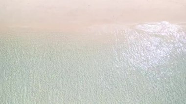 Beyaz kum plajını kristal berrak sığ suyla yıkayan yumuşak dalgaların yukarıdan aşağı görüntüsü. Minimum tropik kıyı şeridi yapısı seyahat geçmişi, doğa konsepti, yaz tanıtımı için idealdir..