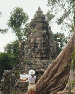 Antik Angkor tapınağı kalıntılarını araştıran haritalı bir kadın gezgin, modern seyahat tanıtımı için konsept resim, macera turizmi reklamı ve küresel seyahat şehveti kampanyaları.