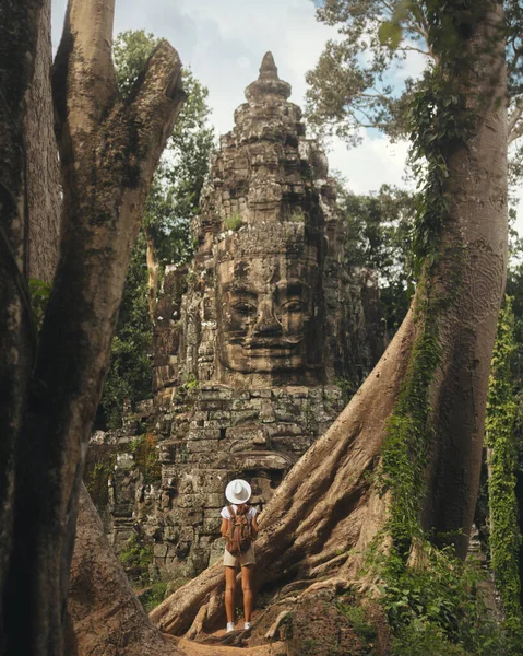 Kamboçya ormanının derinliklerinde antik Bayon taşına hayran kalan kadın turist, kavramsal yüksek kaliteli seyahat promosyonu imajı macera turizmi, kültürel keşif ve editoryal projeler için ideal..