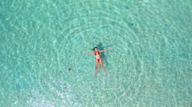 Açık denizde deniz yıldızlarıyla dinlenen bir kadının drone çekimi, seyahat ilhamı, deniz hayatı temaları, yaz tatilleri ve lüks turizm pazarlaması için ideal yüksek kaliteli moda görüntüler..