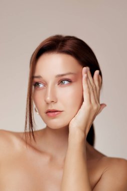 Kusursuz derisi ve çıplak makyajı olan beyaz bir kadın yüzünü güzellik konsepti portresine bastırıyor. Cilt bakımı, yaşlanma karşıtı, yüz gerdirme ya da kozmetik tedavi kampanyaları için ideal..