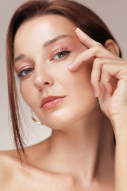 Göz altı bölgesini parmağıyla hafifçe bastıran bir kadının detaylı görüntüleri. Parlak cilt ve yumuşak makyajı gösteriyor. Yaşlanma önleyici, kırışıklık önleyici tedaviler ve göz kremi kampanyaları için ideal..