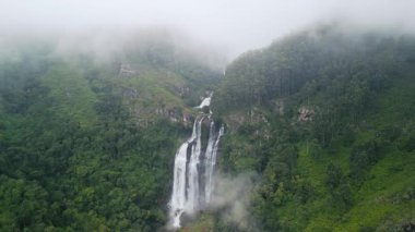 İnsansız hava araçları Nuwara Eliya, Sri Lanka yakınlarındaki Bomburu Ella Şelalesi 'ni gösteriyor. Etrafı yemyeşil orman ve alçak bulutlarla çevrili. Destansı vahşi doğa havası, turizm pazarlaması, belgeseller, macera içeriği için mükemmel..