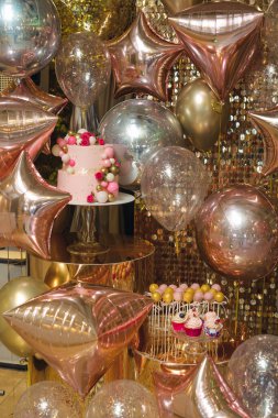 Gül rengi altın ve gümüş balonlar, bir parti tatlı sergisi etrafında pembe pasta, kek ve kek parçaları ile parıltılı bir arkaplandalar. Etkinlik ilanları, davetiyeler, sosyal afişler ve yemek servisi için ideal..