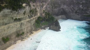 Diamond Beach uçurumları boyunca uçan hava aracı Bali güçlü dalgaları, engebeli kaya oluşumlarını ve aşağıdaki kumlu körfezi yakalıyor. Çarpıcı tropikal manzara seyahat pazarlama ve markalaşma için mükemmel..