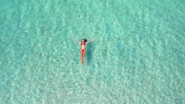 Hava aracının üstü açık kırmızı bikinili neşeli bir kadının sığ turkuvaz sularda yüzdüğünü gösteriyor. Deniz yıldızı sahili, Phu Quoc Adası, Vietnam. Seyahat reklamları, turizm ve tatil beldeleri için ideal..