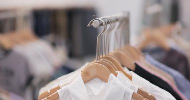 Perakende satış mağazasındaki ahşap askılarda beyaz elbiseler üzerinde hareket eden yakın çekim görüntüleri. Yumuşak doğal aydınlatma ve sığ alan derinliği. Moda reklamları için mükemmel..