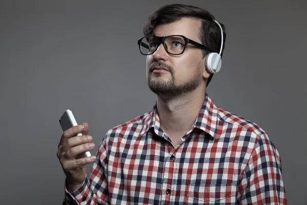 Ο σύγχρονος άνθρωπος όμορφος hipster ακούσετε μουσική στα ακουστικά. — Φωτογραφία Αρχείου