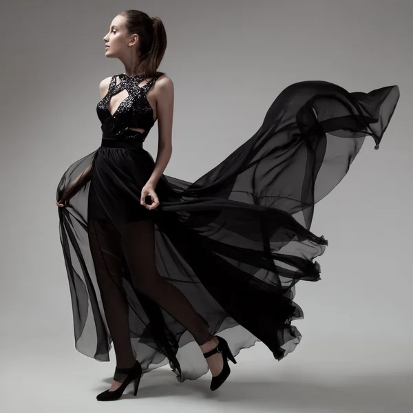 Mulher de moda em fluttering vestido preto. Fundo cinzento . — Fotografia de Stock